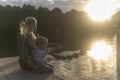 Mom and son with blond hair sit on the bridge to the shore of the lake during sunset Royalty Free Stock Photo