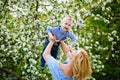 Mom and son in a blooming apple orchard in spring. A woman holds a child in her arms, plays and has fun with it