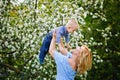 Mom and son in a blooming apple orchard in spring. A woman holds a child in her arms, plays and has fun with it