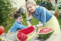 Mom and son cut a watermelon and laugh in the garden. Love and tenderness