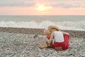 Mom and son embrace on a pebble beach. Sunset time. Back view Royalty Free Stock Photo