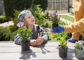 mom and son are getting ready to plant flowers together in garden. plants are arranged oe table on sunny spring day Royalty Free Stock Photo