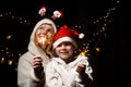 Mom and son are happy and smiling with sparklers in their hands. Woman with a boy in Christmas hats in the dark Royalty Free Stock Photo