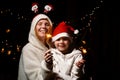 Mom and son are happy and smiling with sparklers in their hands. Woman with a boy in Christmas hats in the dark Royalty Free Stock Photo