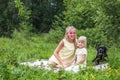 Mom and son are hugging on a blanket in the park. Close-up portrait. Woman in pink sunglasses. A large black dog lies nearby