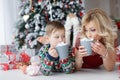 Mom and son lie near the New Year tree with big cups of cappuccino and marshmallows Royalty Free Stock Photo