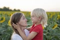Mom and son make each other`s faces. Cheerful portrait of mother and son on sunflower field background Royalty Free Stock Photo