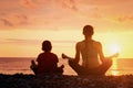 Mom and son meditate on the beach in lotus position. View from t