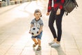 Mom and son play football together outdoors in the park, Little boy kicks a soccer ball, child learns to play football Royalty Free Stock Photo