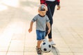 Mom and son play football together outdoors in the park, Little boy kicks a soccer ball, child learns to play football Royalty Free Stock Photo