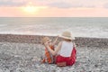 Mom and son play on the pebble beach. Sunset time. Back view Royalty Free Stock Photo