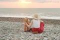 Mom and son play on the pebble beach. Sunset time. Back view Royalty Free Stock Photo