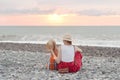 Mom and son play on the pebble beach. Sunset time. Back view Royalty Free Stock Photo