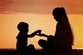 Mom and son playing on the beach with stones. Sunset time, silho Royalty Free Stock Photo