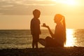 Mom and son playing on the beach with stones. Sunset time, silhouettes Royalty Free Stock Photo