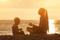 Mom and son playing on the beach with stones. Sunset time, silhouettes Royalty Free Stock Photo