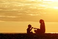 Mom and son playing on the beach with stones. Sunset time, silhouettes Royalty Free Stock Photo