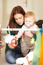 Mom and son playtime. Cute young mom sitting alongside her infant son and holding him while he plays. Royalty Free Stock Photo