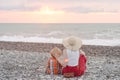 Mom and son rest on the pebble beach. Sunset time. Back view Royalty Free Stock Photo