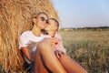 Mom and son are resting in a haystack in a field at sunset. Happy family hugging and kissing. Love and tenderness Royalty Free Stock Photo