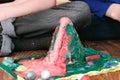 Mom and son`s hands make experience with plasticine volcano at home. Chemical reaction with gas emission.