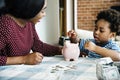 Mom and son saving money to piggy bank