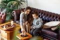 Mom and son sit on sofa living room  building tower from wooden blocks  taking tiles in turn from underneath untill it falls. Royalty Free Stock Photo