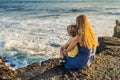 Mom and son are sitting on a rock and looking at the sea. Portrait travel tourists - mom with kids. Positive human Royalty Free Stock Photo