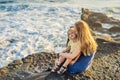 Mom and son are sitting on a rock and looking at the sea. Portrait travel tourists - mom with kids. Positive human Royalty Free Stock Photo