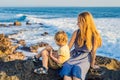 Mom and son are sitting on a rock and looking at the sea. Portrait travel tourists - mom with kids. Positive human Royalty Free Stock Photo