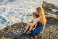 Mom and son are sitting on a rock and looking at the sea. Portrait travel tourists - mom with kids. Positive human Royalty Free Stock Photo