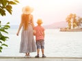 Mom and son standing on the pier on the sea background, lighthouse and mountains in the distance. Back view Royalty Free Stock Photo