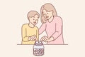 Mom and son together throw coins into moneybox, wanting to save up money for cherished wish