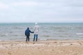 Mom and son are walking on the sea sand beach in winter, back view. Beautiful view of the sand and snow storm on the Royalty Free Stock Photo