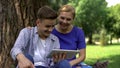 Mom and son watching funny video on tablet, surfing net in park, time together Royalty Free Stock Photo