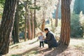 Mom squatted down in front of a little girl on a path in the forest