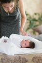 Mom swaddles the baby. A woman is swaddling a small child on the couch. The kid laughs fun. The woman also smiles. They are in a Royalty Free Stock Photo