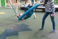 Mom swing son on empty webbed swing. Royalty Free Stock Photo