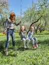 Mom swings her kids on the garden swing Royalty Free Stock Photo