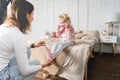 Mom takes off her little daughter`s socks and tickles her feet a little. The girl laughs. Royalty Free Stock Photo