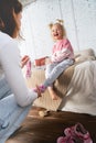 Mom takes off her little daughter`s socks and tickles her feet a little. The girl laughs. Royalty Free Stock Photo