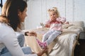 Mom takes off her little daughter`s socks and tickles her feet a little. The girl laughs. Royalty Free Stock Photo