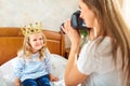 Mom takes pictures of her child in a room by the window. Royalty Free Stock Photo