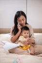 A mom is talking on the phone and working on documents while taking care of her little son Royalty Free Stock Photo