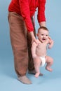 Mom teaches the child to stand on his feet and walk, baby boy on a blue studio background Royalty Free Stock Photo
