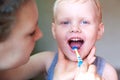 Mom teaches and helps her three-year-old son to brush his teeth Royalty Free Stock Photo