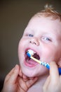 Mom teaches and helps her three-year-old son to brush his teeth Royalty Free Stock Photo