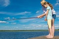 Mom teaches her daughter to fish, outdoors, standing on the pier, against the blue sky Royalty Free Stock Photo