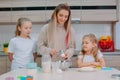 Mom teaches her daughters to cook dough in the kitchen