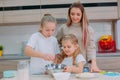 Mom teaches her daughters to cook dough in the kitchen